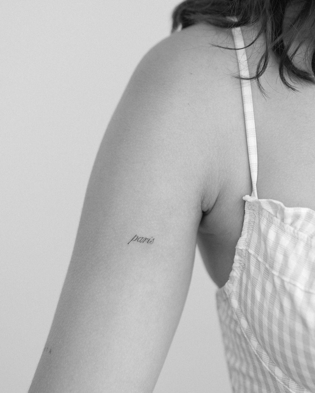 Tattoo de palabra en tipografía serif sobre el brazo
